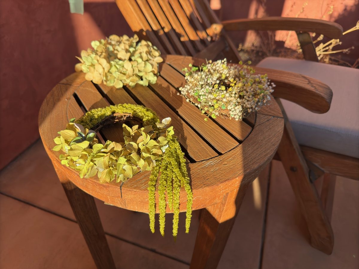 Variety of mini wreaths and preserved flowers on outdoor table