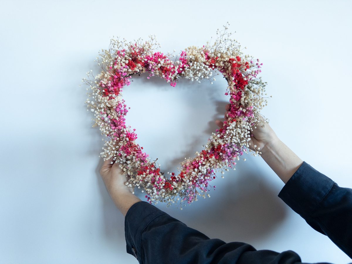 Heart-shaped preserved flower wreath held by the maker